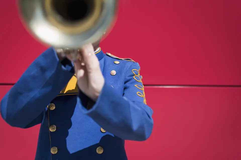 Trompeter in blauer Uniform vor roter Wand