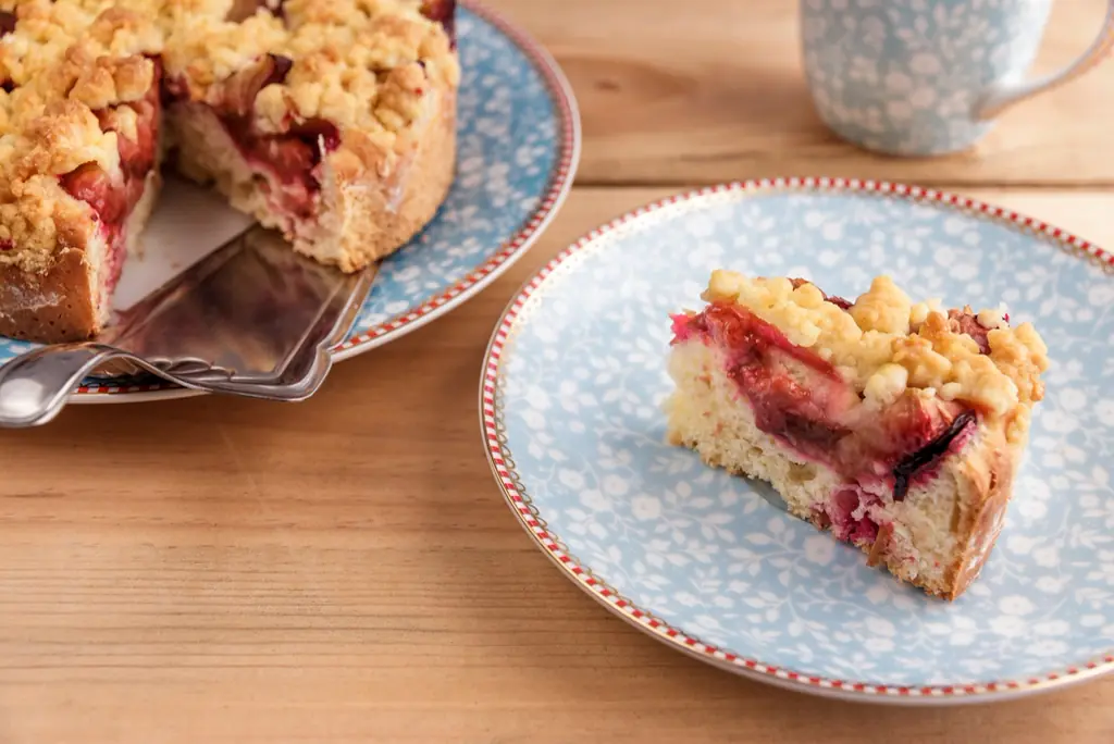 Ein Stück Pflaumenkuchen mit Streuseln auf einem blauen Teller