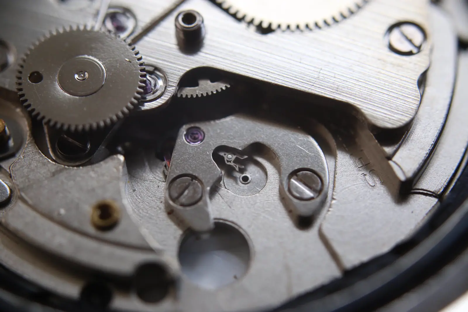 Nahaufnahme eines mechanischen Uhrwerks mit Zahnrädern und gebläuten Schrauben