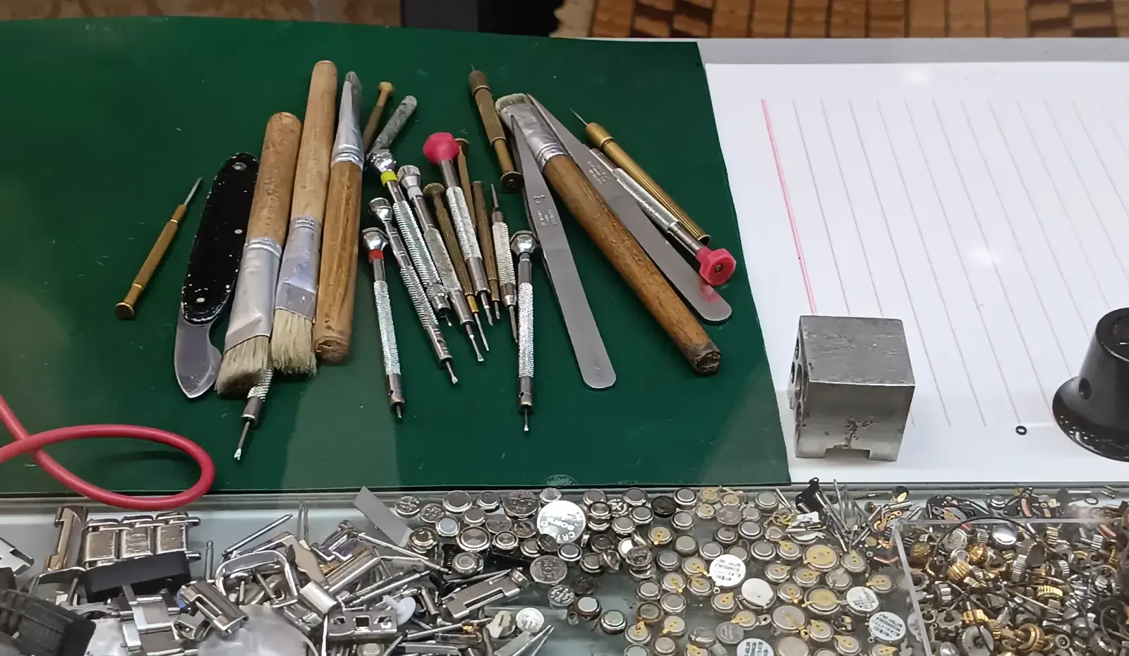 Schraubendreher, Pinsel und Pinzetten auf grüner Werkbankunterlage