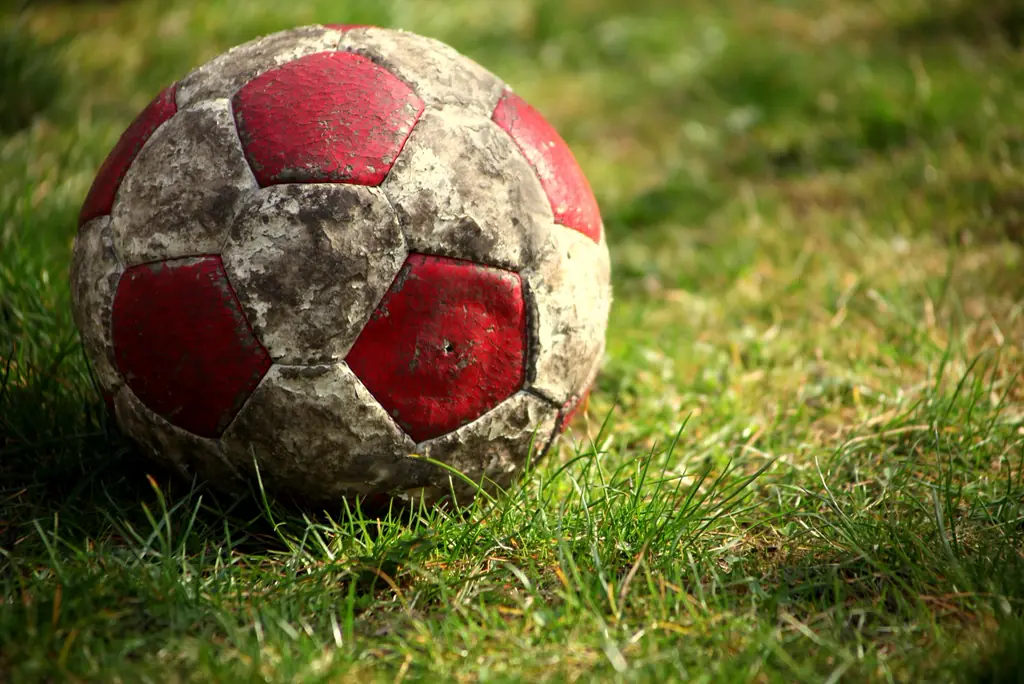 Ein abgenutzter Fußball liegt im Gras